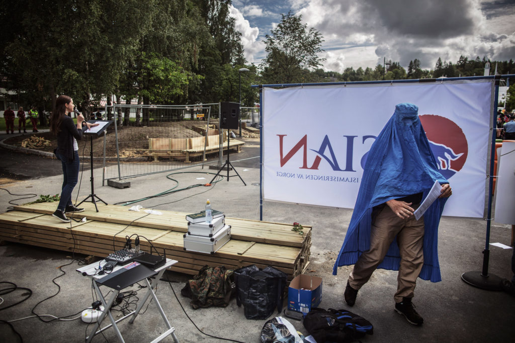 Medan Margarita talar inför åhörarna som samlats på Furuset torg i Oslo, klär sig en annan SIAN-medlem i burka för att väcka reaktioner.