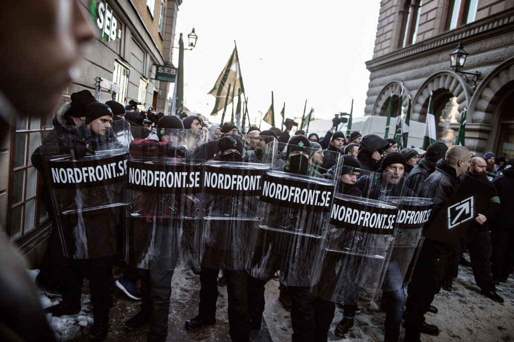 Medlemmar i Nordiska motståndsrörelsen skyddar sig med sköldar under sin hittills största demonstration i Stockholm, i november 2016.